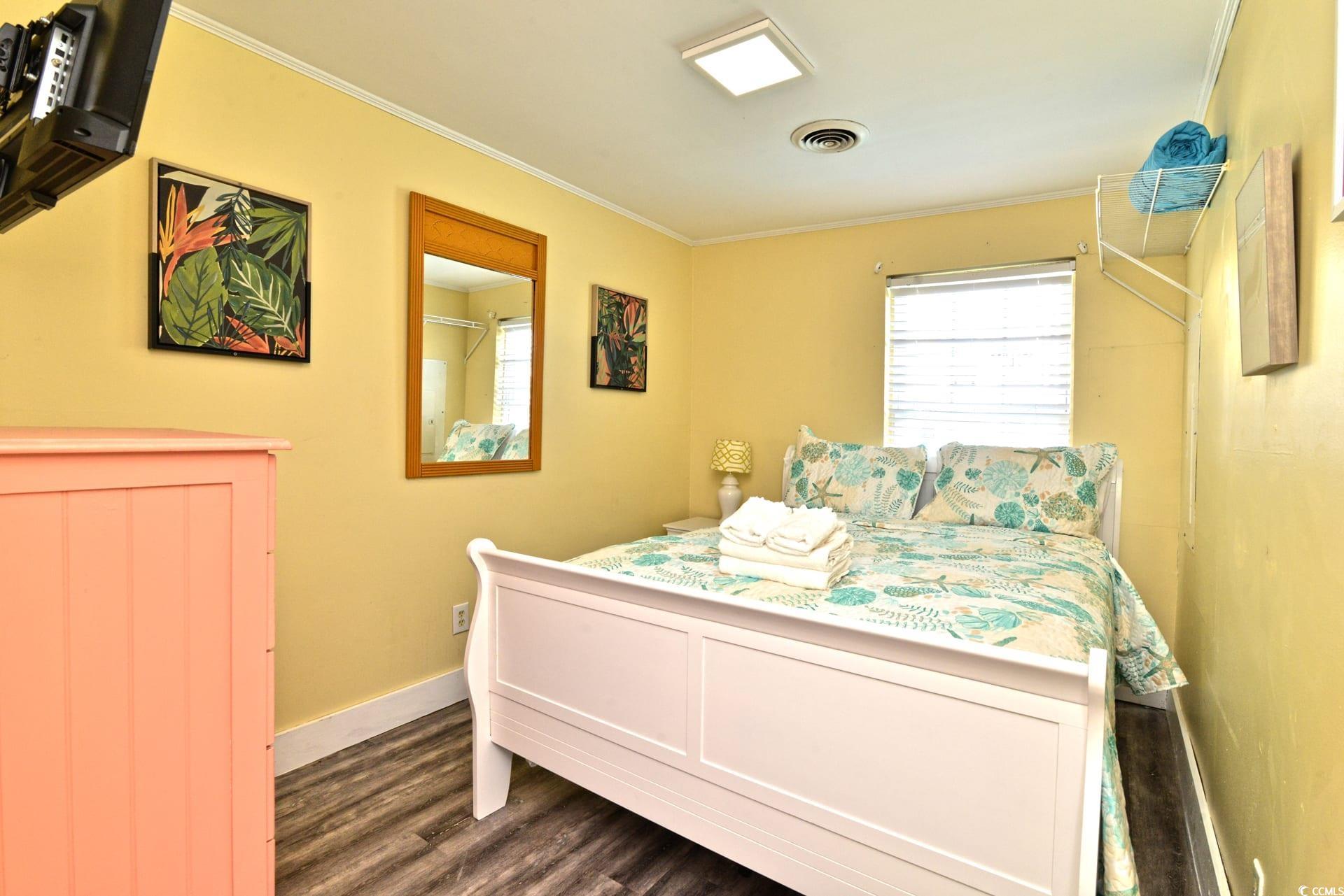 219 27th Avenue North North Myrtle Beach, SC 29582 - Photo 23 of 34 Bedroom featuring baseboards, ornamental molding, dark wood-style floors, and visible vents