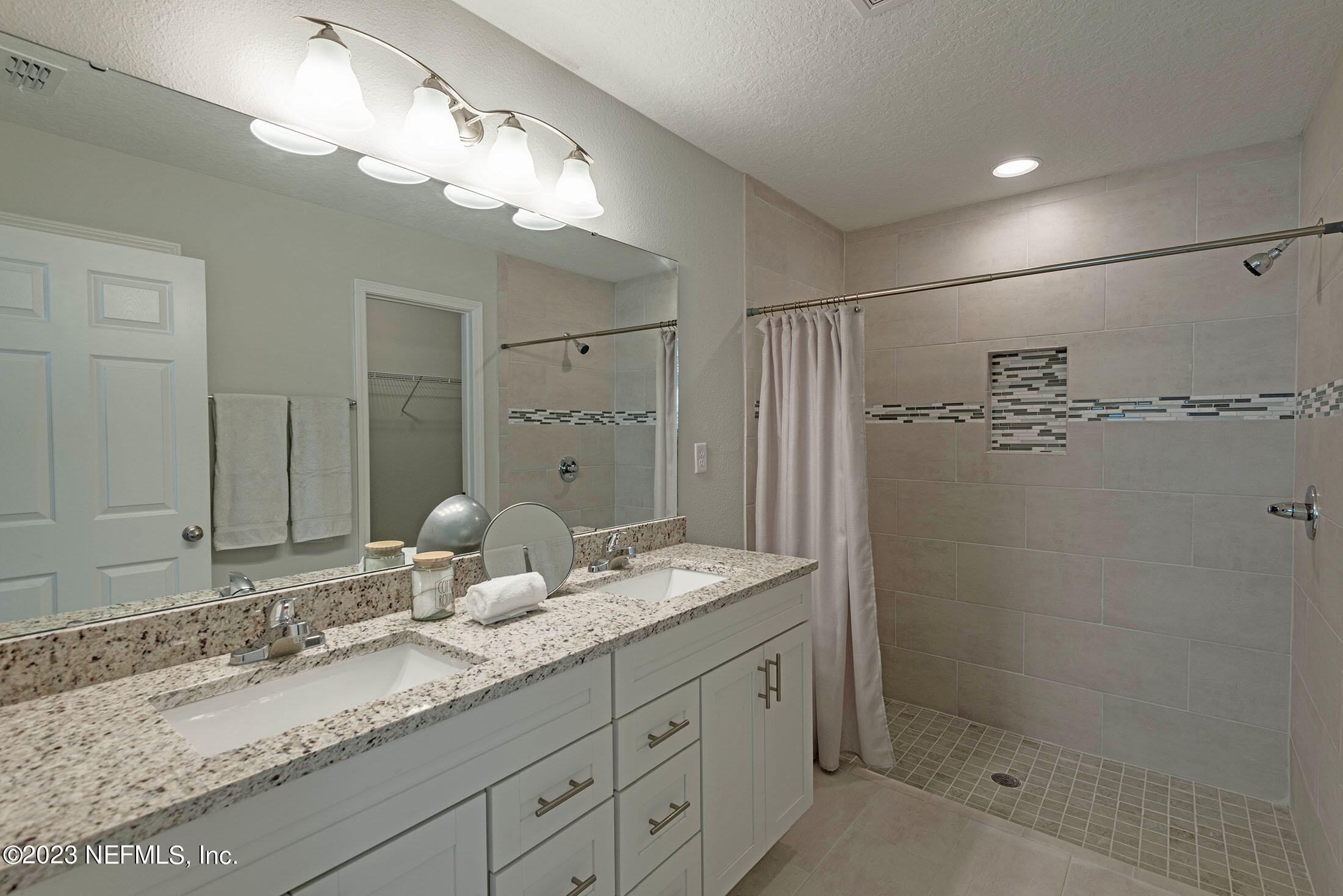 7298 Wheat Road Jacksonville, FL 32244 - Photo 23 of 40 a bathroom with a granite countertop sink a mirror and a shower