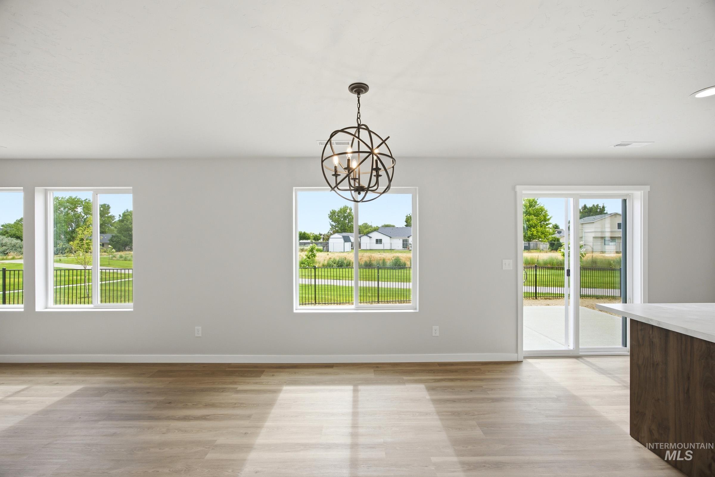 14044 Shiny Spruce Street Caldwell, ID 83607 - Photo 6 of 24 Spacious interior with wood-finish flooring, light gray walls, and a contemporary spherical chandelier