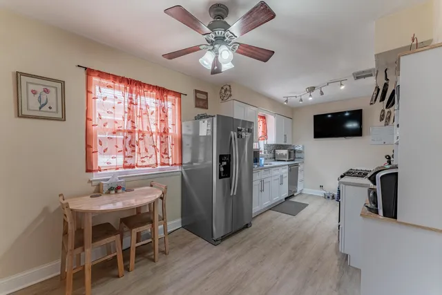 a kitchen with stainless steel appliances granite countertop a refrigerator a stove a sink a dining table and chairs with wooden floor