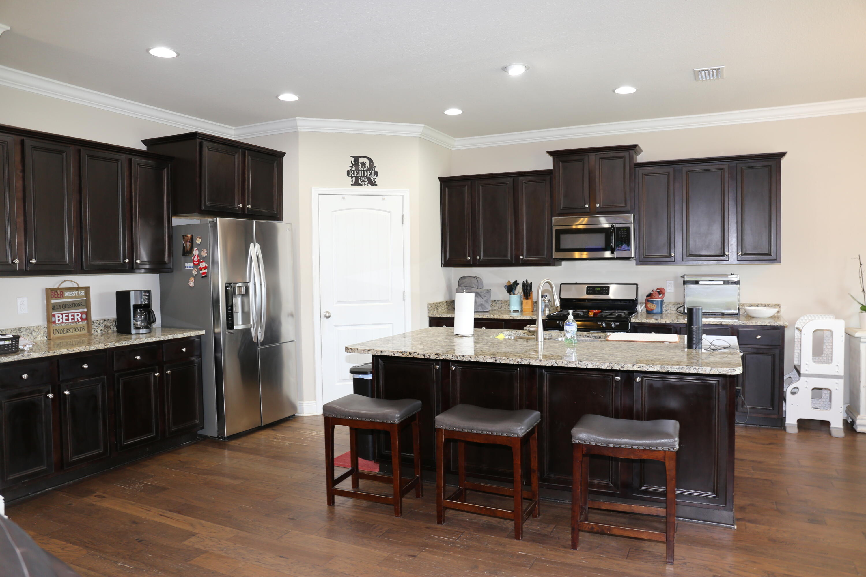 400 Lilly Bell Lane, Unit LOT 26 Freeport, FL 32439 - Photo 14 of 43 a kitchen with kitchen island granite countertop wooden cabinets a refrigerator a stove a microwave a island with a dining table and chairs