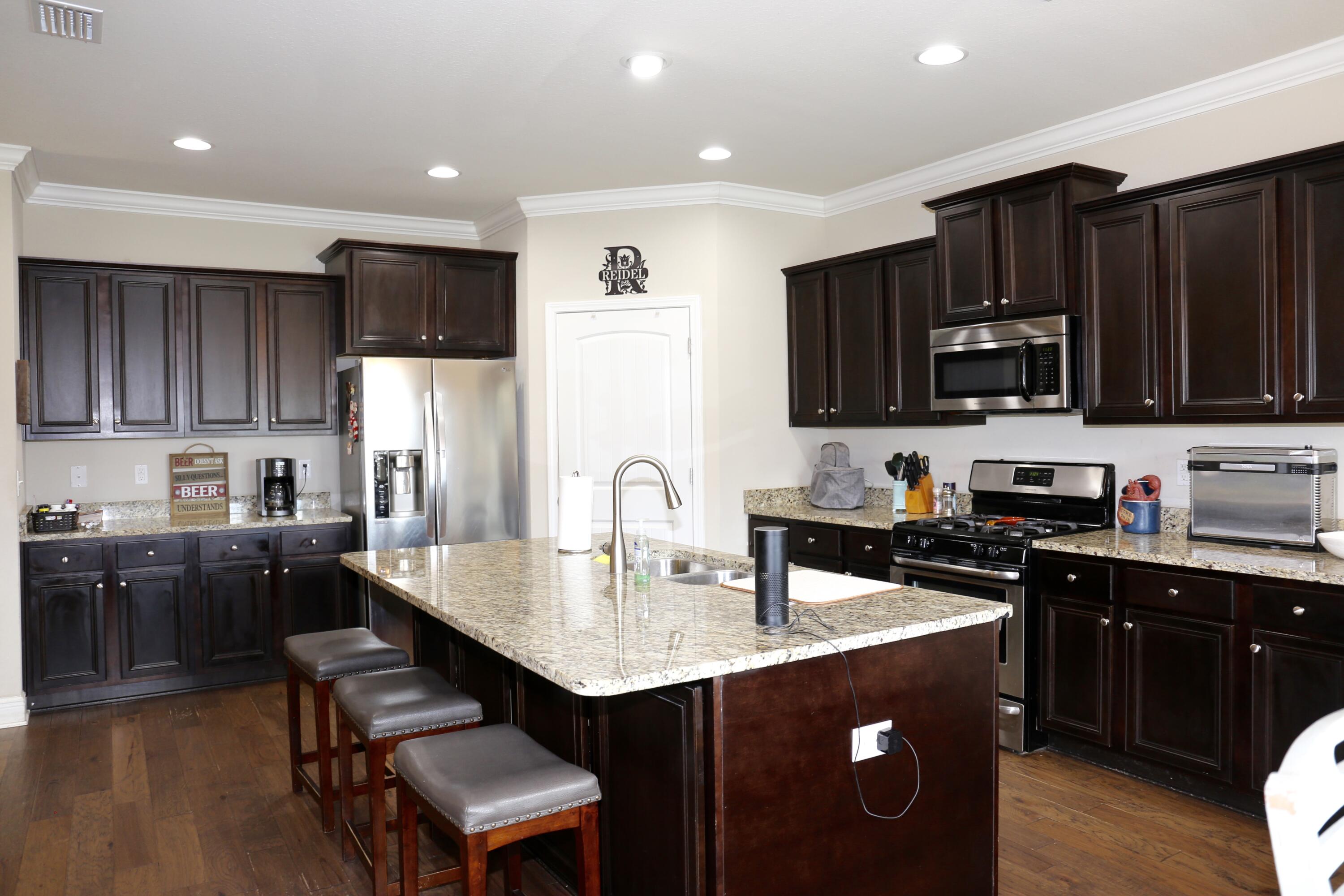 400 Lilly Bell Lane, Unit LOT 26 Freeport, FL 32439 - Photo 15 of 43 a kitchen with granite countertop a refrigerator a stove top oven a sink and wooden cabinets