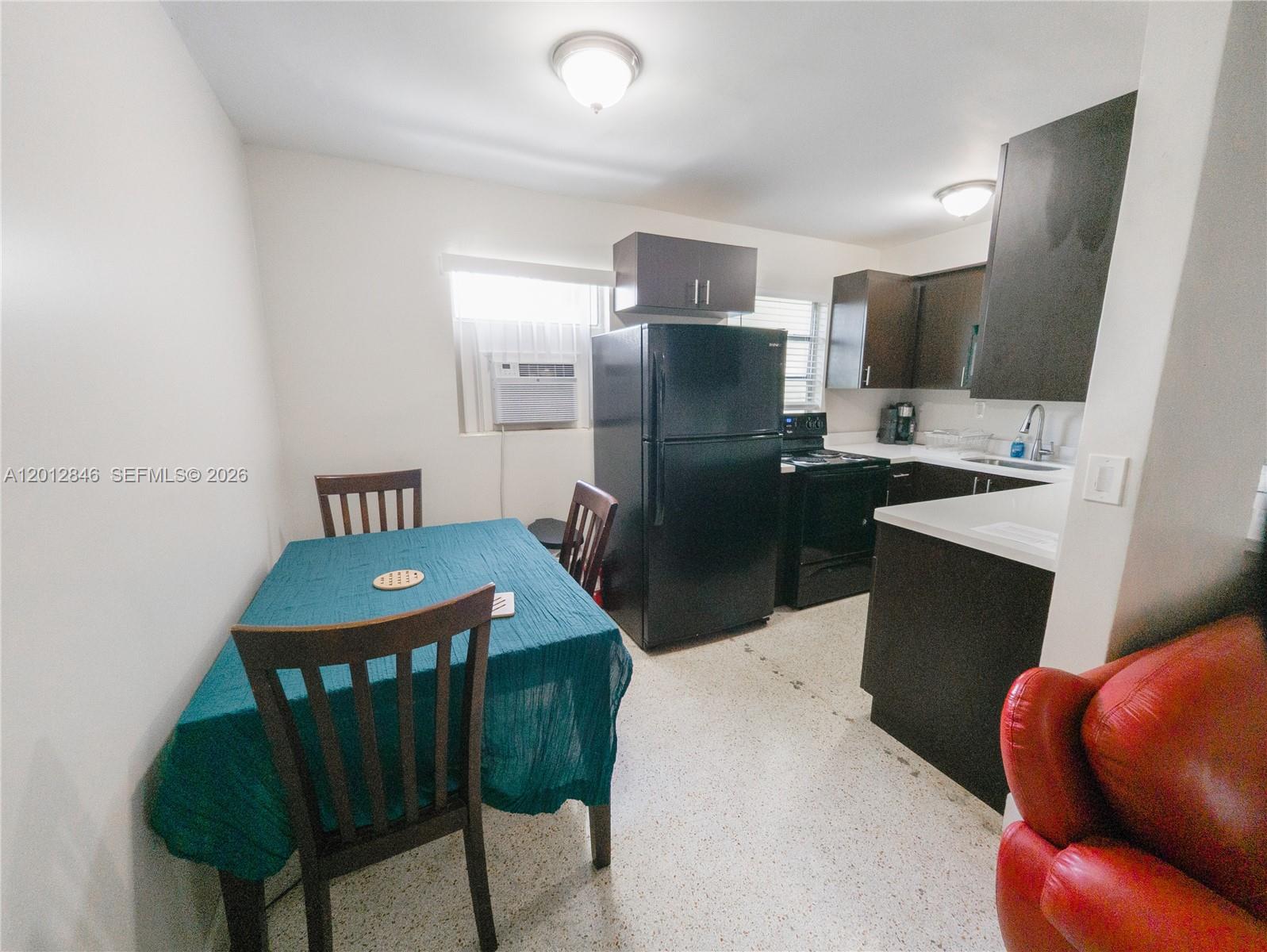 1220 Southwest 5th Street, Unit 16 Miami, FL 33135 - Photo 4 of 8 a kitchen with stainless steel appliances kitchen island granite countertop a sink a stove a refrigerator with a dining table and chairs