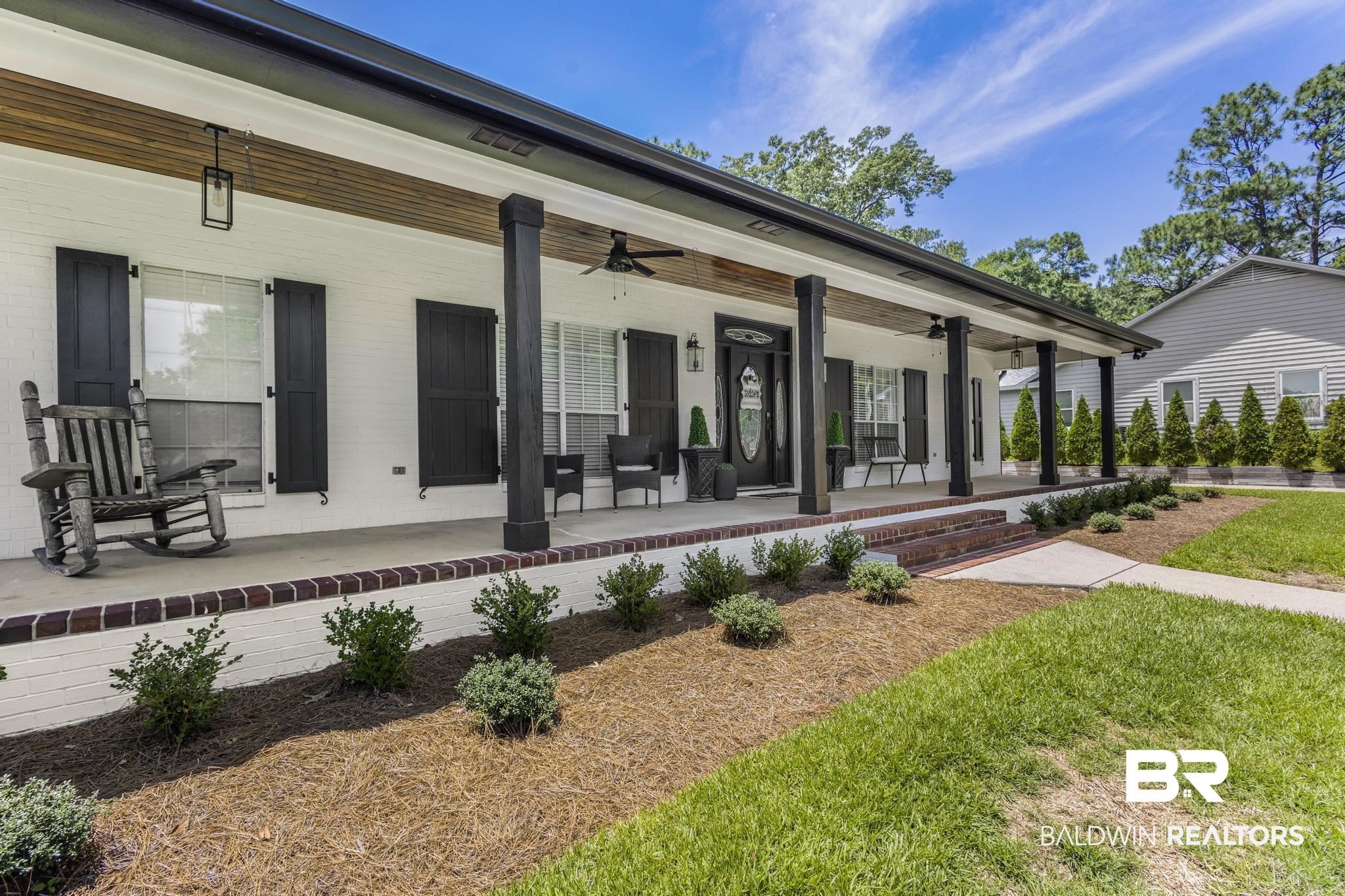 83 Caisson Trace Daphne, AL 36527 - Photo 5 of 63 White brick exterior with black shutters and a wood-finish porch ceiling