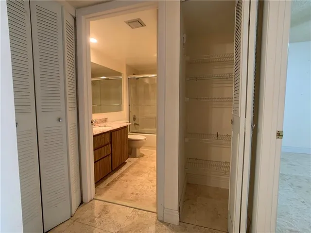 a bathroom with a granite countertop sink toilet mirror and bathtub