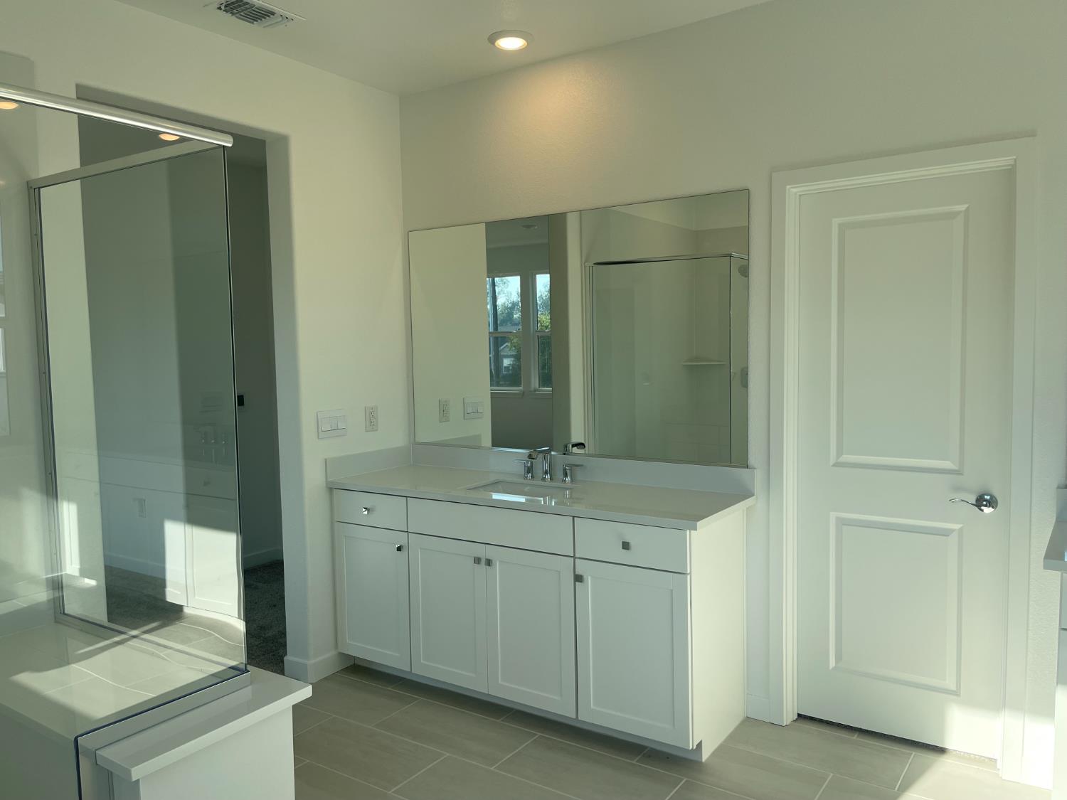 8512 Cottonseed Way Elk Grove, CA 95624 - Photo 8 of 9 a bathroom with a granite countertop sink a mirror and a shower