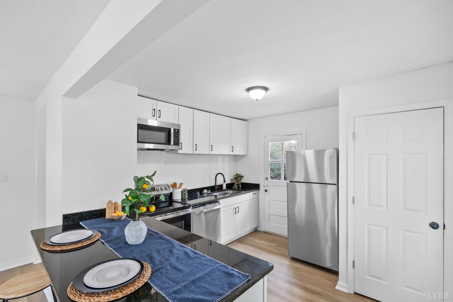 1201 Brandon Road Lynchburg, VA 24502 - Photo 5 of 25 a kitchen with stainless steel appliances a white refrigerator a stove a sink dishwasher and white cabinets with wooden floor