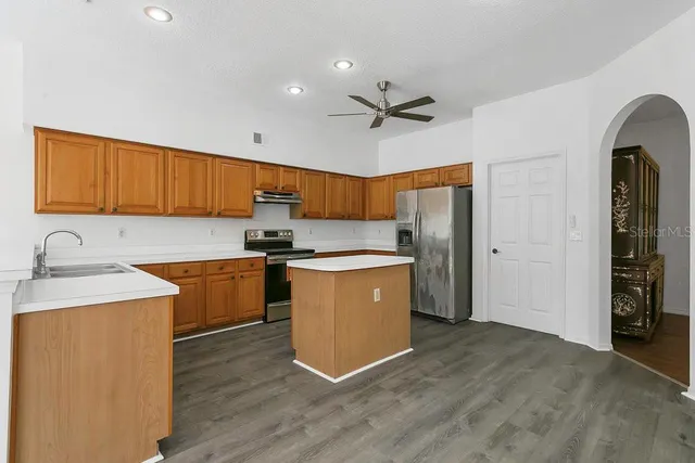 a kitchen with stainless steel appliances granite countertop a refrigerator a sink dishwasher a stove with wooden cabinets and a granite counter top