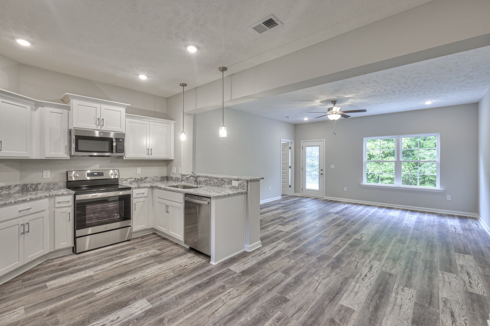 113 Creek Wood Road Manchester, TN 37355 - Photo 1 of 37 a large kitchen with kitchen island granite countertop a stove top oven a sink dishwasher and white cabinets with wooden floor