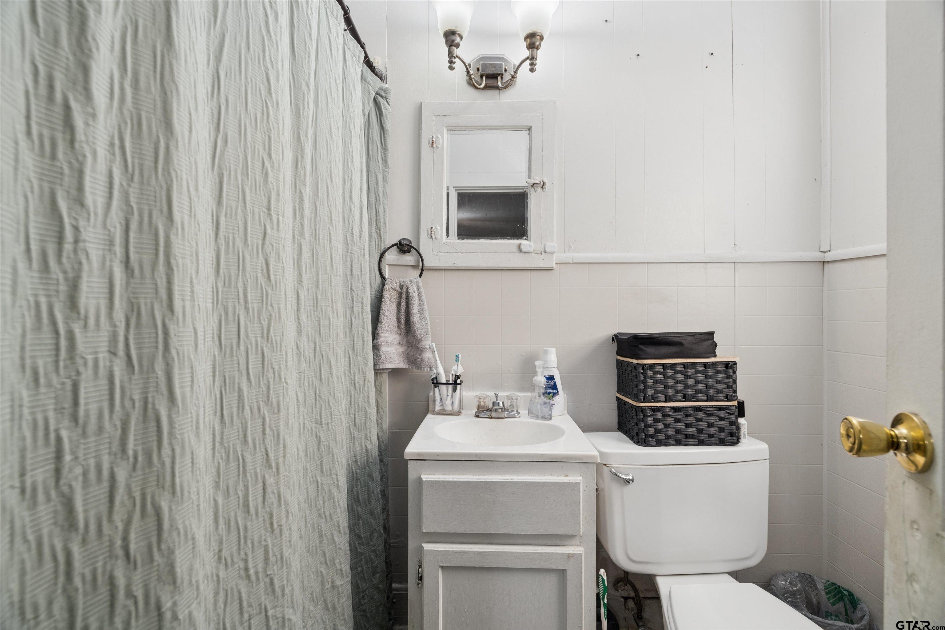 1010 Maple Street Kilgore, TX 75662 - Photo 5 of 20 a bathroom with a sink a toilet and shower curtain