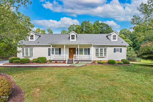 a front view of a house with a garden and trees