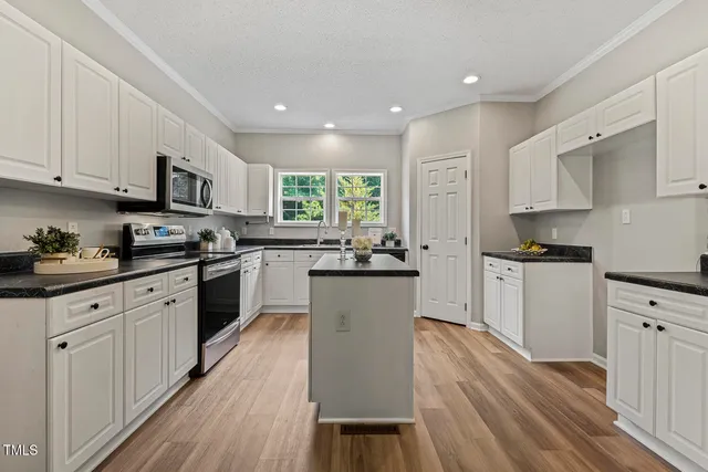 a kitchen with granite countertop white cabinets and white appliances