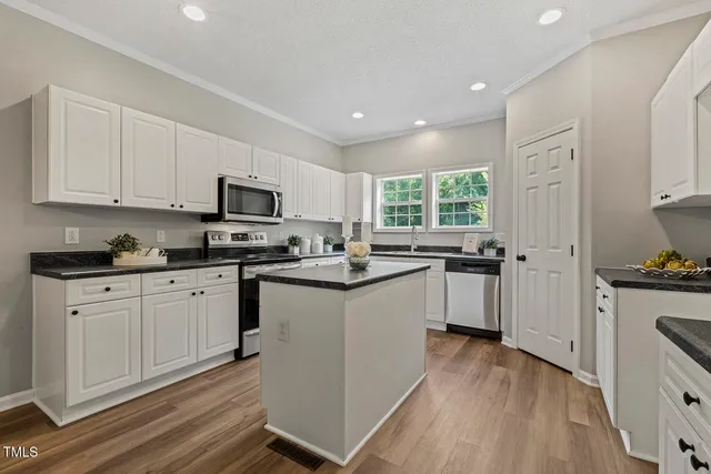 a kitchen with granite countertop white cabinets large appliances a sink and dishwasher