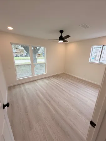 an empty room with windows and ceiling fan