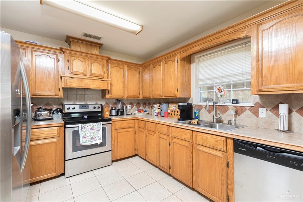 1801 Largo Street Weslaco, TX 78596 - Photo 3 of 20 a kitchen with stainless steel appliances granite countertop a stove sink and cabinets