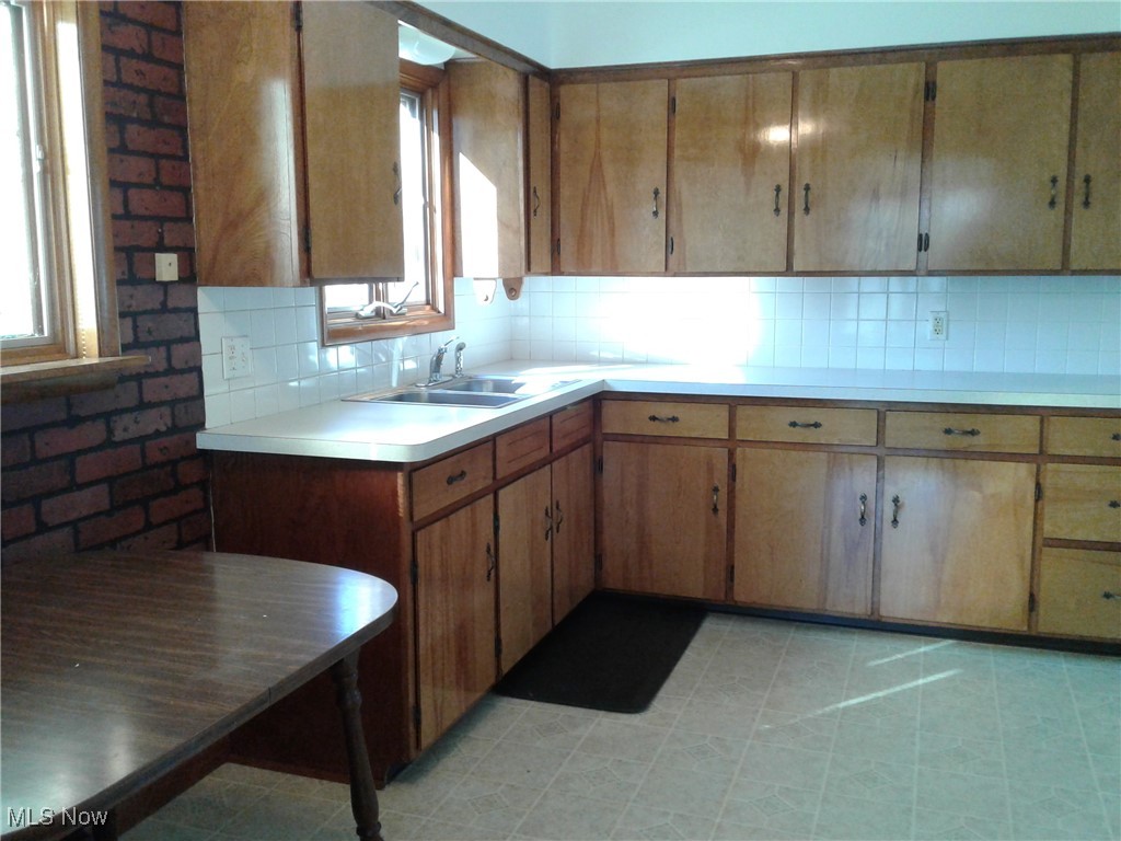 332 Claremont Road Vermilion, OH 44089 - Photo 6 of 35 Kitchen featuring light countertops, brown wood cabinets, tasteful backsplash, and a sink