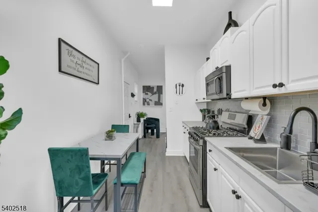 a kitchen with stainless steel appliances a white table and chairs in it