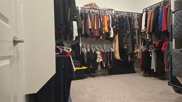 a view of walk in closet with clothes and shoes