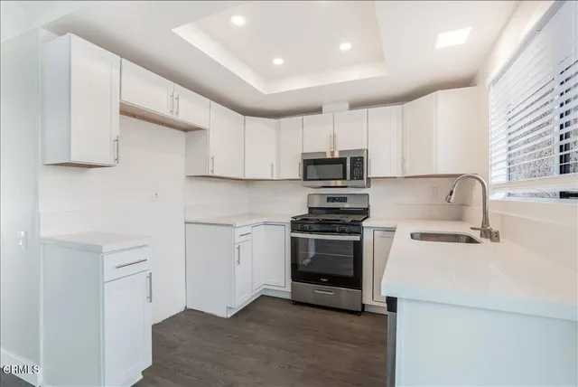a kitchen with stainless steel appliances a stove a sink a microwave and cabinets