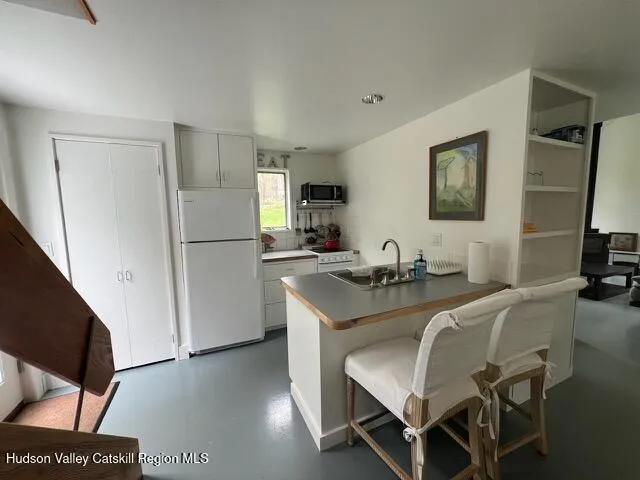 a kitchen with granite countertop a refrigerator a stove a sink a dining table and chairs