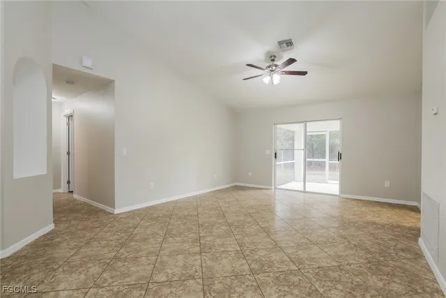 an empty room with chandelier fan and windows