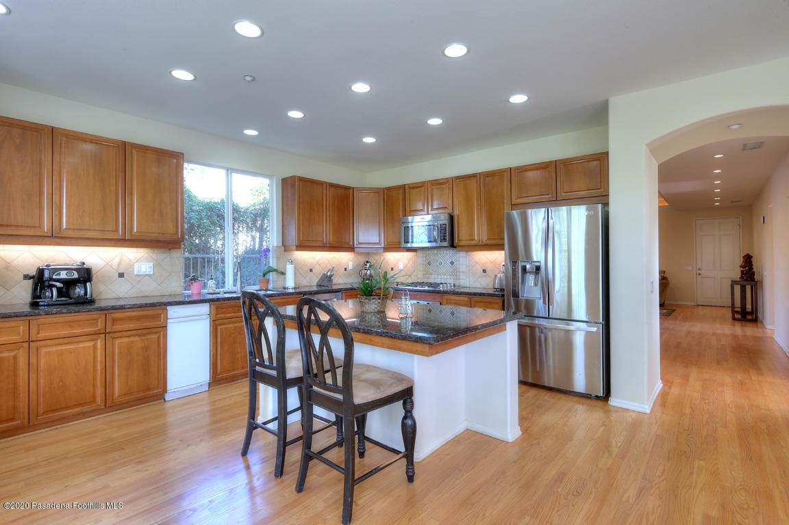 7461 Chanteclair Court Tujunga, CA 91042 - Photo 9 of 44 a kitchen with stainless steel appliances granite countertop a refrigerator a sink a stove a dining table and chairs with wooden floor