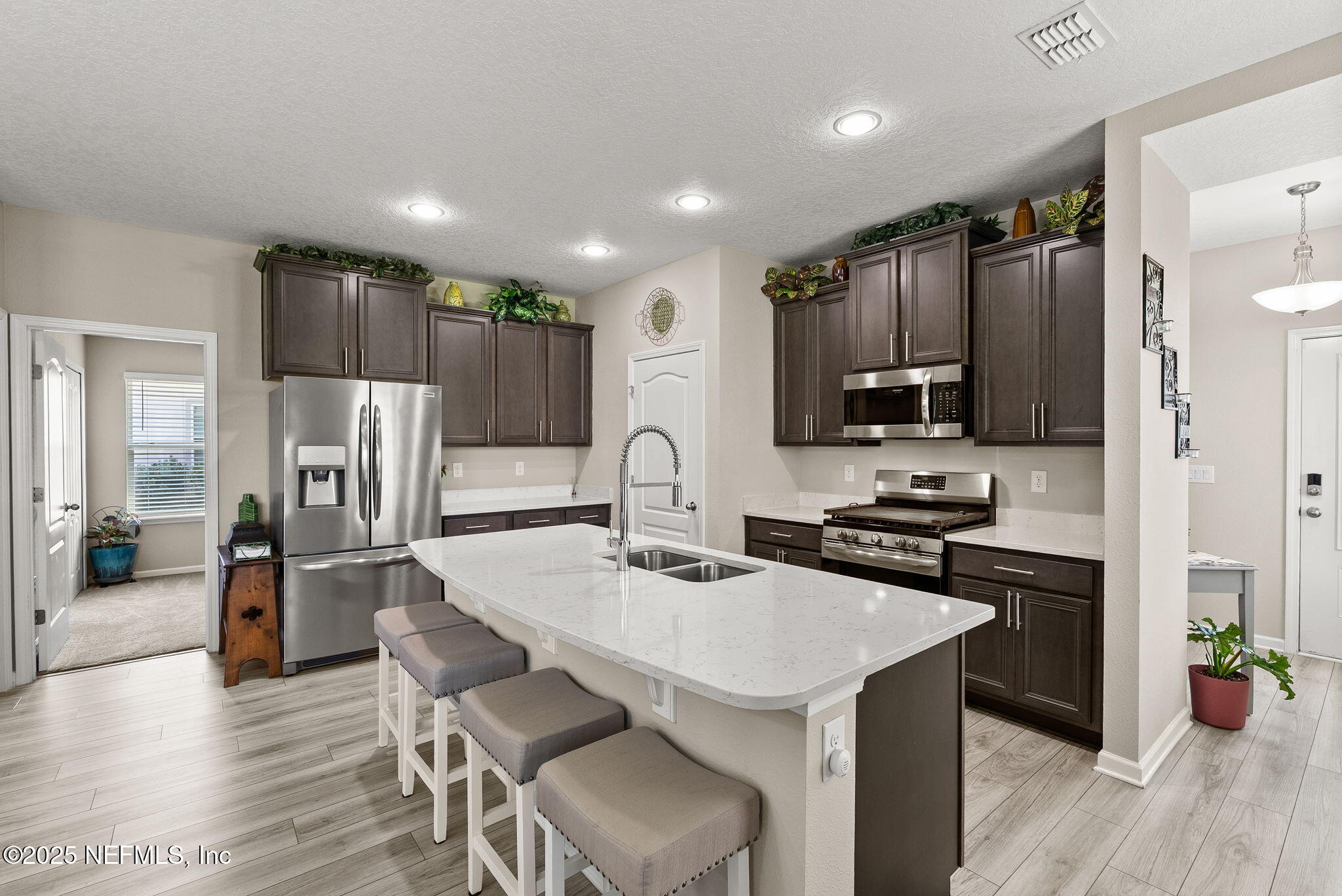 3961 Heatherbrook Place Middleburg, FL 32068 - Photo 4 of 28 a kitchen with stainless steel appliances a stove a sink a refrigerator white cabinets and wooden floor