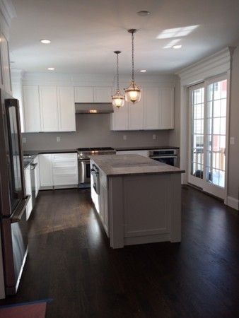 57 Upland Road Needham, MA 02492 - Photo 4 of 10 a kitchen with stainless steel appliances granite countertop a stove a sink a refrigerator white cabinets and wooden floor next to a window
