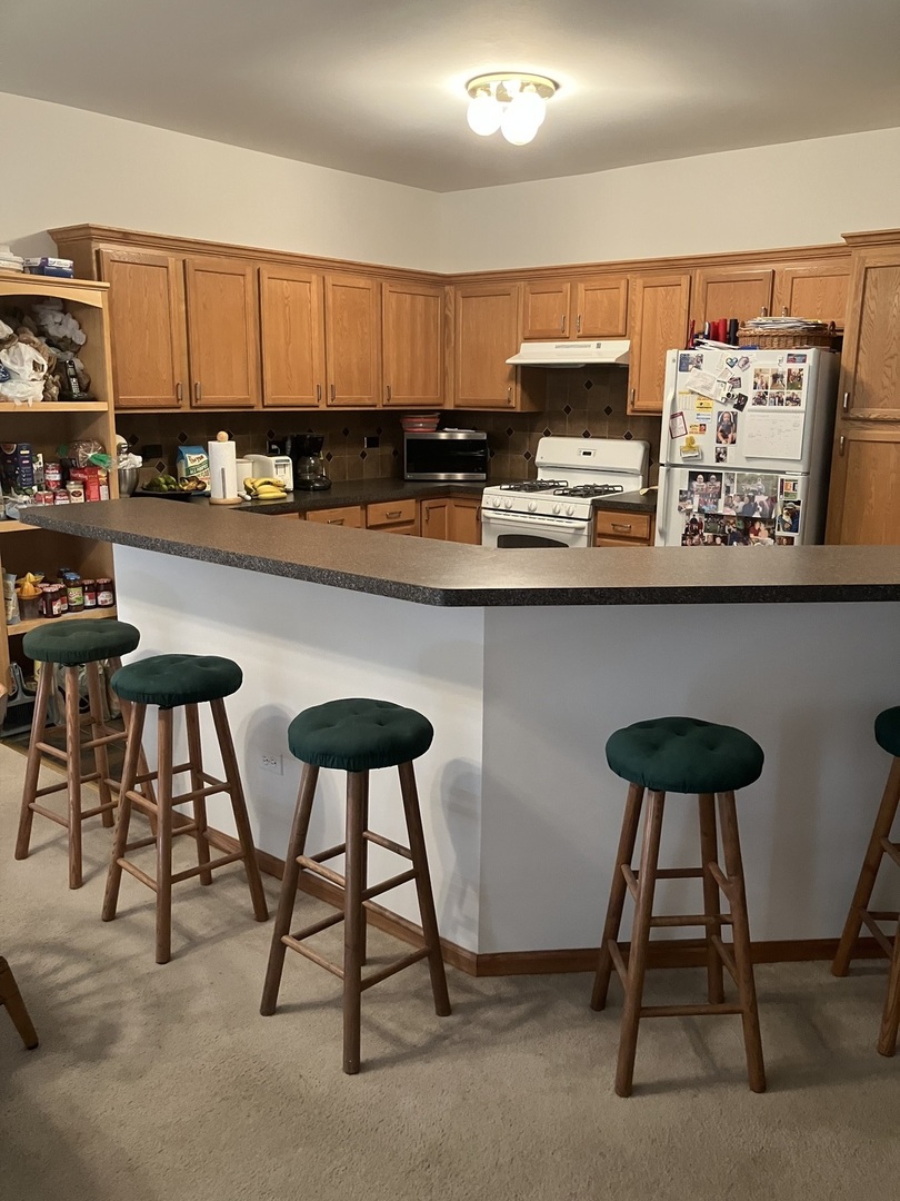 19246 104th Avenue Mokena, IL 60448 - Photo 25 of 38 a kitchen with stainless steel appliances granite countertop a table chairs in it and wooden floors