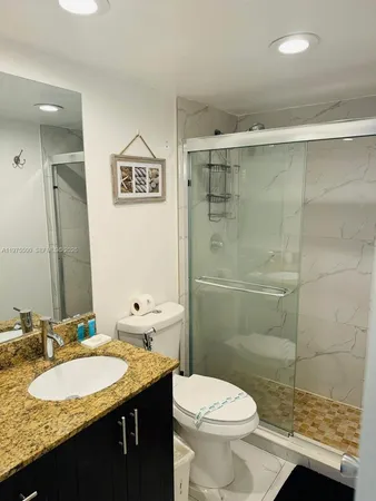 a bathroom with a granite countertop sink mirror vanity and toilet