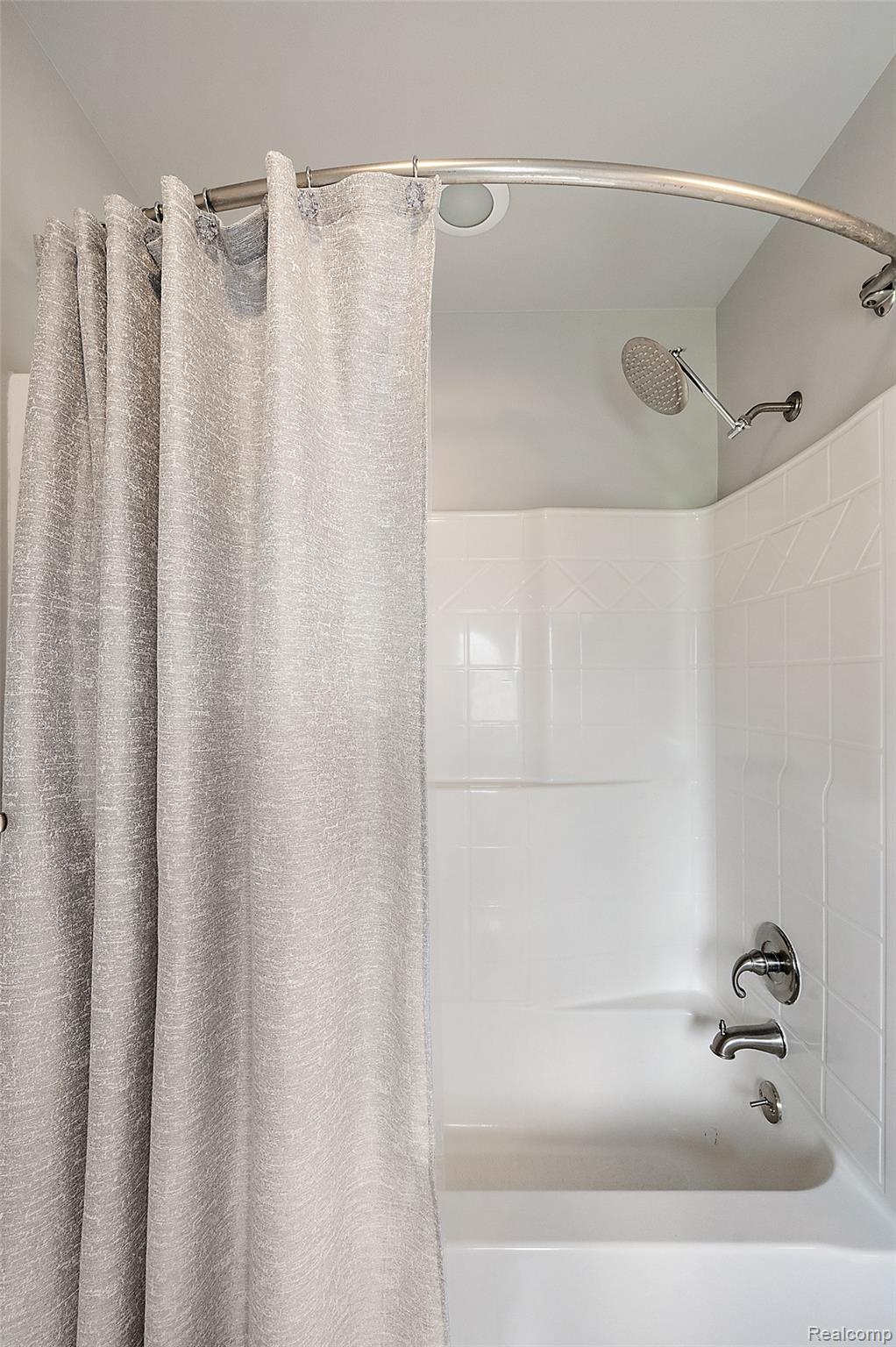5035 Hidden Ridge Road Metamora, MI 48455 - Photo 43 of 65 White tub and shower combination with a curved shower rod, brushed nickel fixtures, and a tiled shower surround