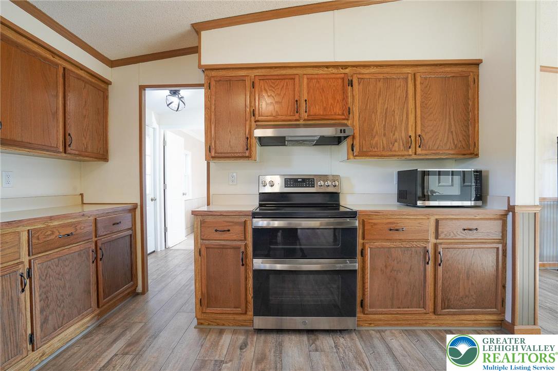 7221 Borman Road New Tripoli, PA 18066 - Photo 24 of 62 a kitchen with stainless steel appliances granite countertop a stove top oven a refrigerator and cabinets with wooden floors