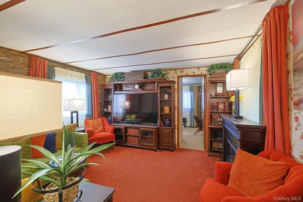 a living room with furniture a flat screen tv and floor to ceiling window