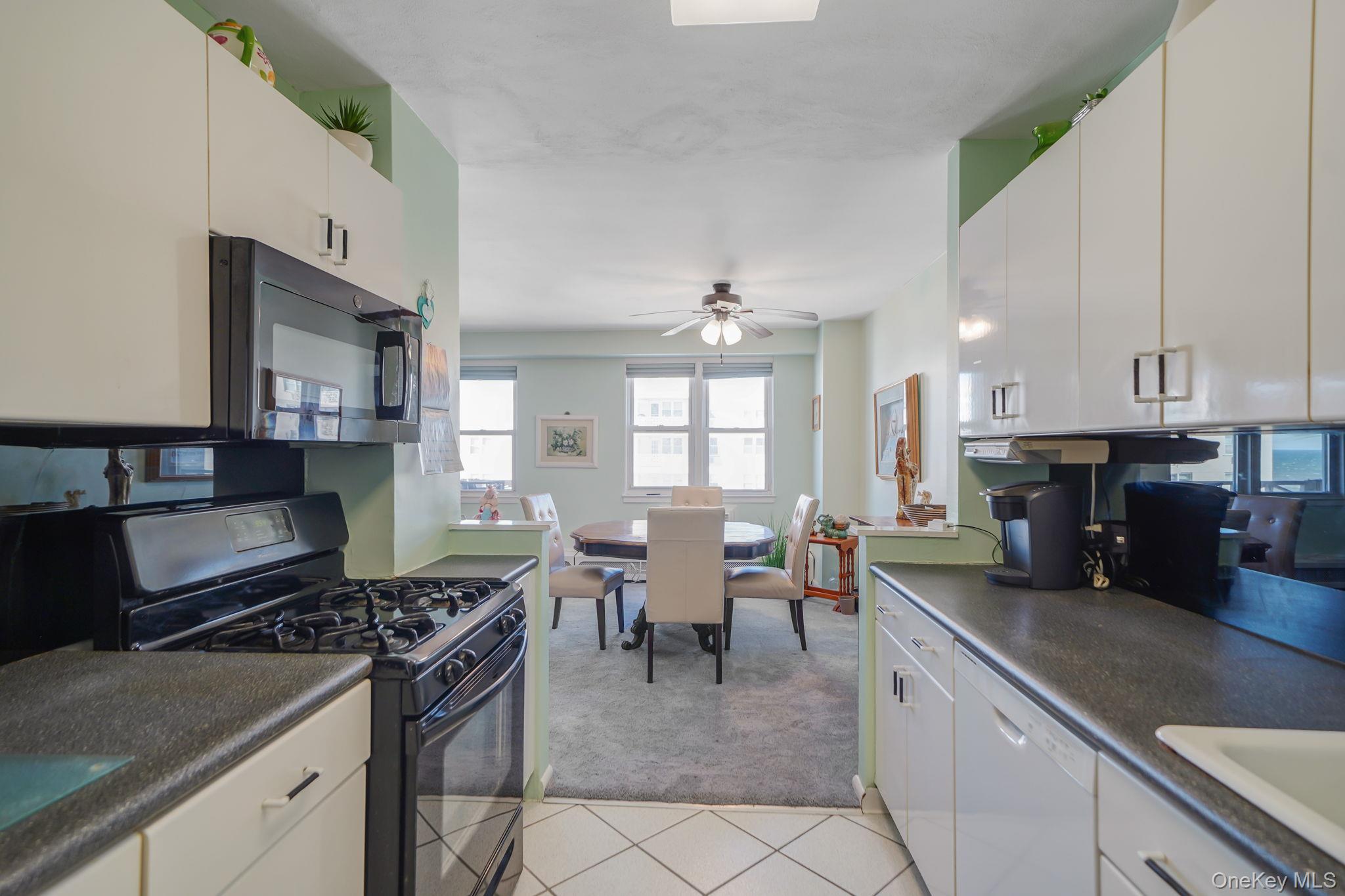 450 Shore Road, Unit 8G Long Beach, NY 11561 - Photo 9 of 19 a kitchen with stainless steel appliances granite countertop a stove top oven a sink a dining table and chairs