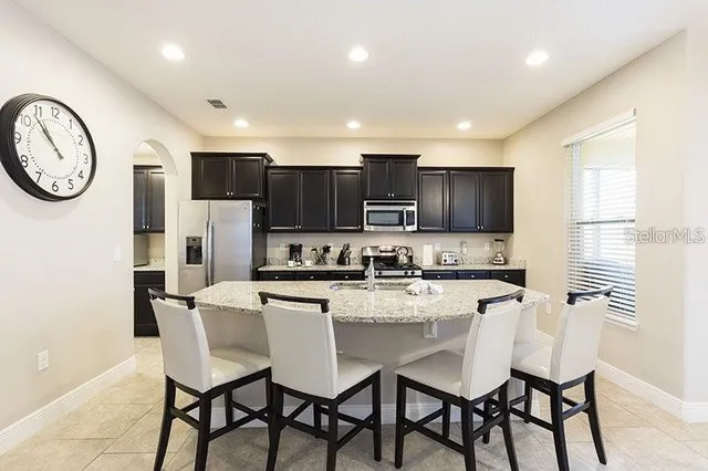 a kitchen with stainless steel appliances granite countertop a table chairs stove microwave and cabinets