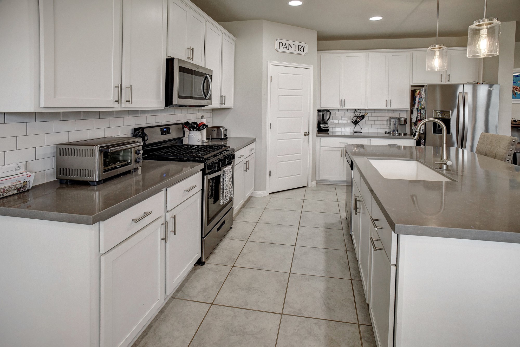 210 Cold Spg Loop Bastrop, TX 78602 - Photo 12 of 40 Kitchen with stainless steel appliances, white cabinetry, light tile patterned floors, and pendant lighting