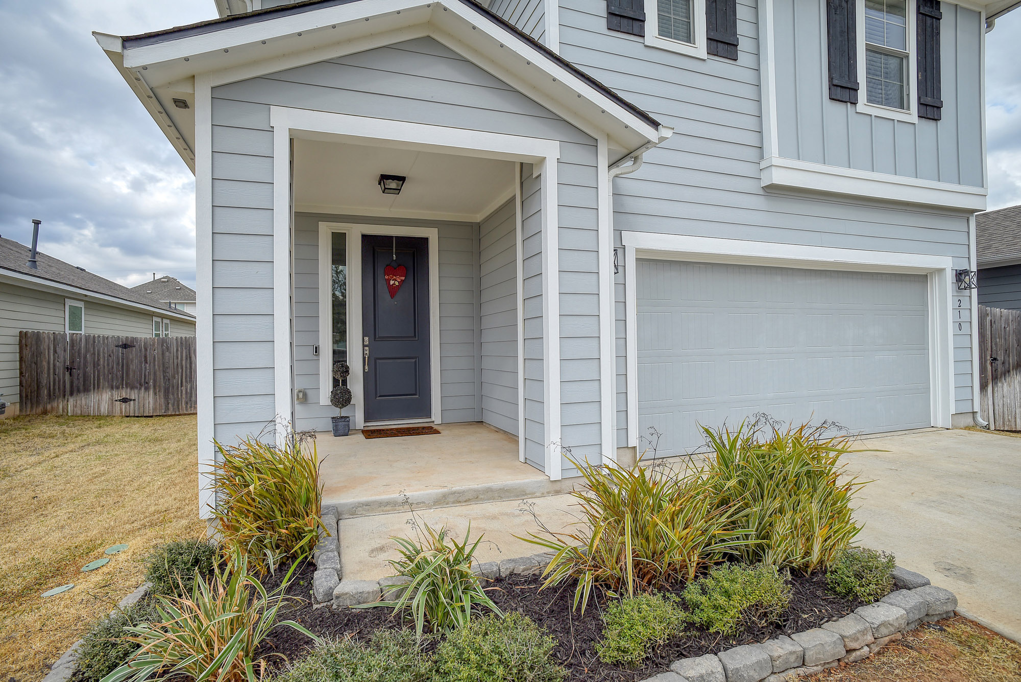 210 Cold Spg Loop Bastrop, TX 78602 - Photo 5 of 40 View of exterior entry with a garage, concrete driveway, and board and batten siding