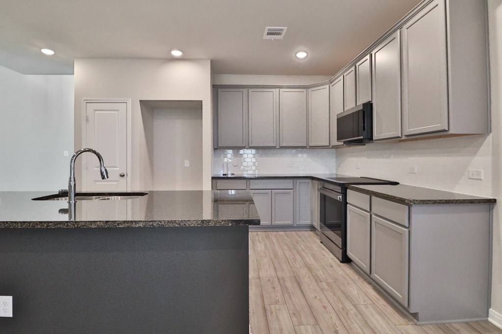 1926 Viva Road Bryan, TX 77807 - Photo 11 of 39 a kitchen with stainless steel appliances granite countertop a stove a sink and a microwave