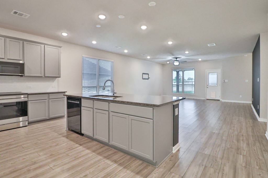 1926 Viva Road Bryan, TX 77807 - Photo 14 of 39 a open kitchen with kitchen island a sink dishwasher stove and white cabinets with wooden floor