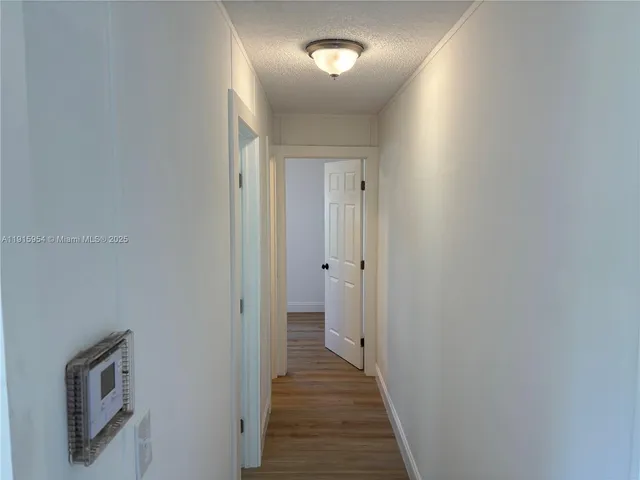 a view of a hallway with wooden floor and a bathroom
