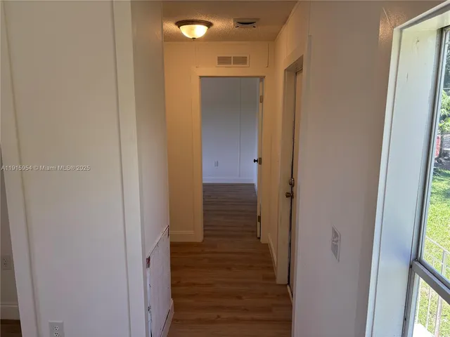 a view of a hallway with wooden floor and staircase