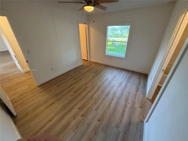 a view of an empty room with wooden floor and window