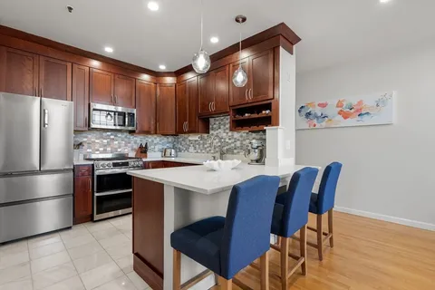 a kitchen with stainless steel appliances a table chairs refrigerator and a sink