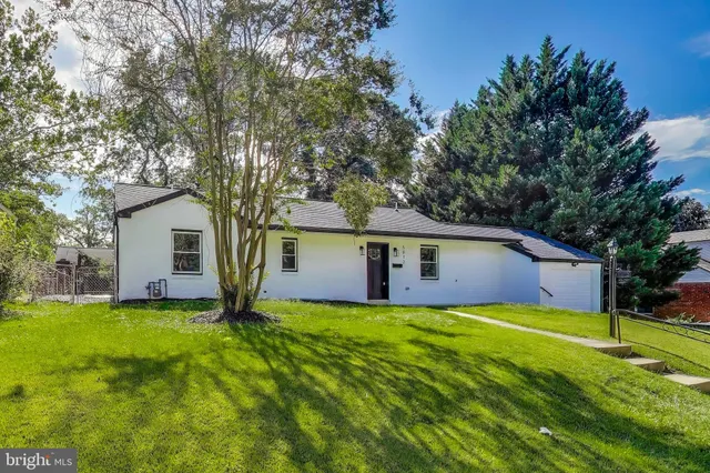 a view of a house with a yard and large trees