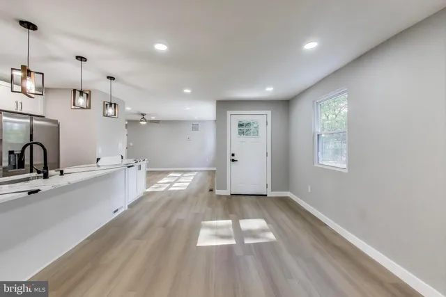 a view of a kitchen with kitchen island a sink wooden floor and appliances