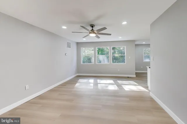 an empty room with chandelier fan and windows