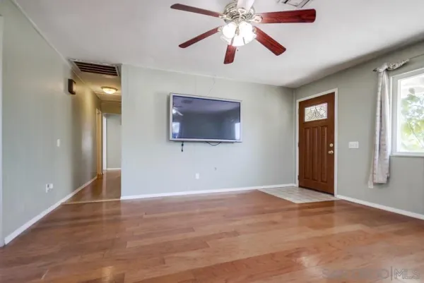 a view of an empty room with window and wooden floor
