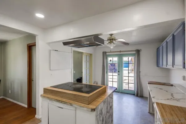 an empty room with wooden floor cabinet and windows