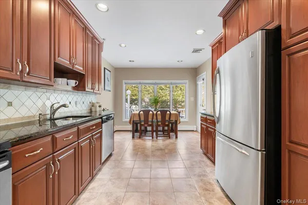 a kitchen with granite countertop a refrigerator a sink a dining table and chairs