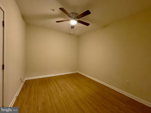 an empty room with wooden floor and ceiling fan